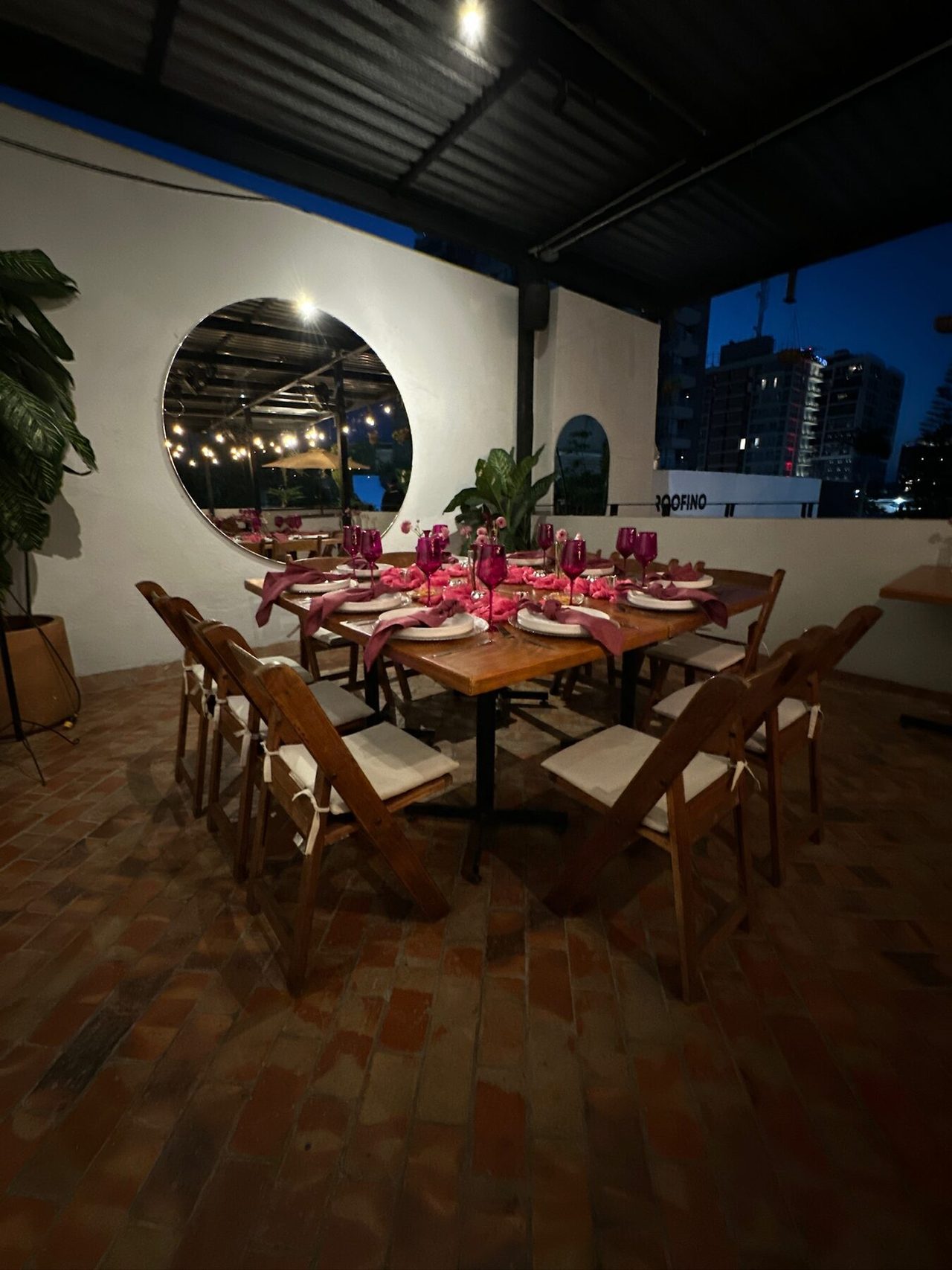 Mesa larga en terraza techada con mantelería vino y candelabros