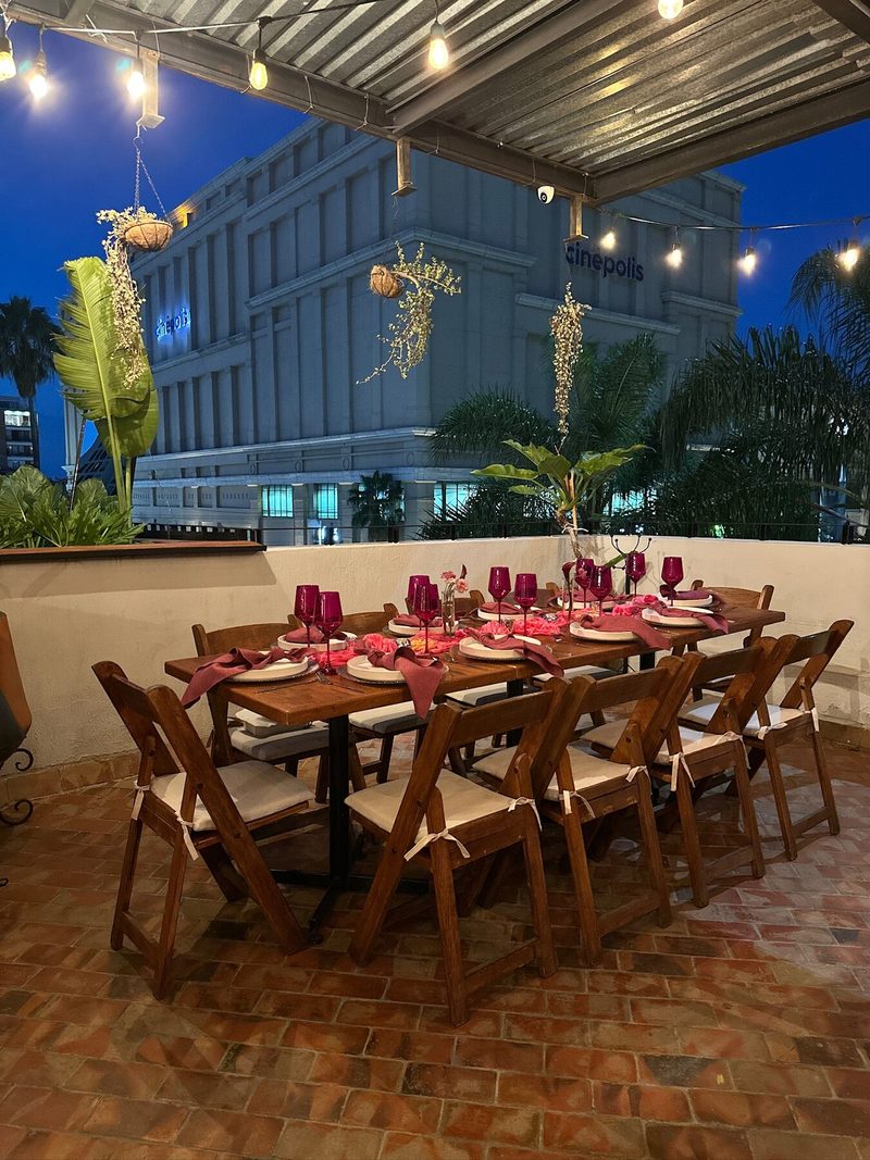 Mesa de rooftop con mantelería vino, flores silvestres y vista a la ciudad