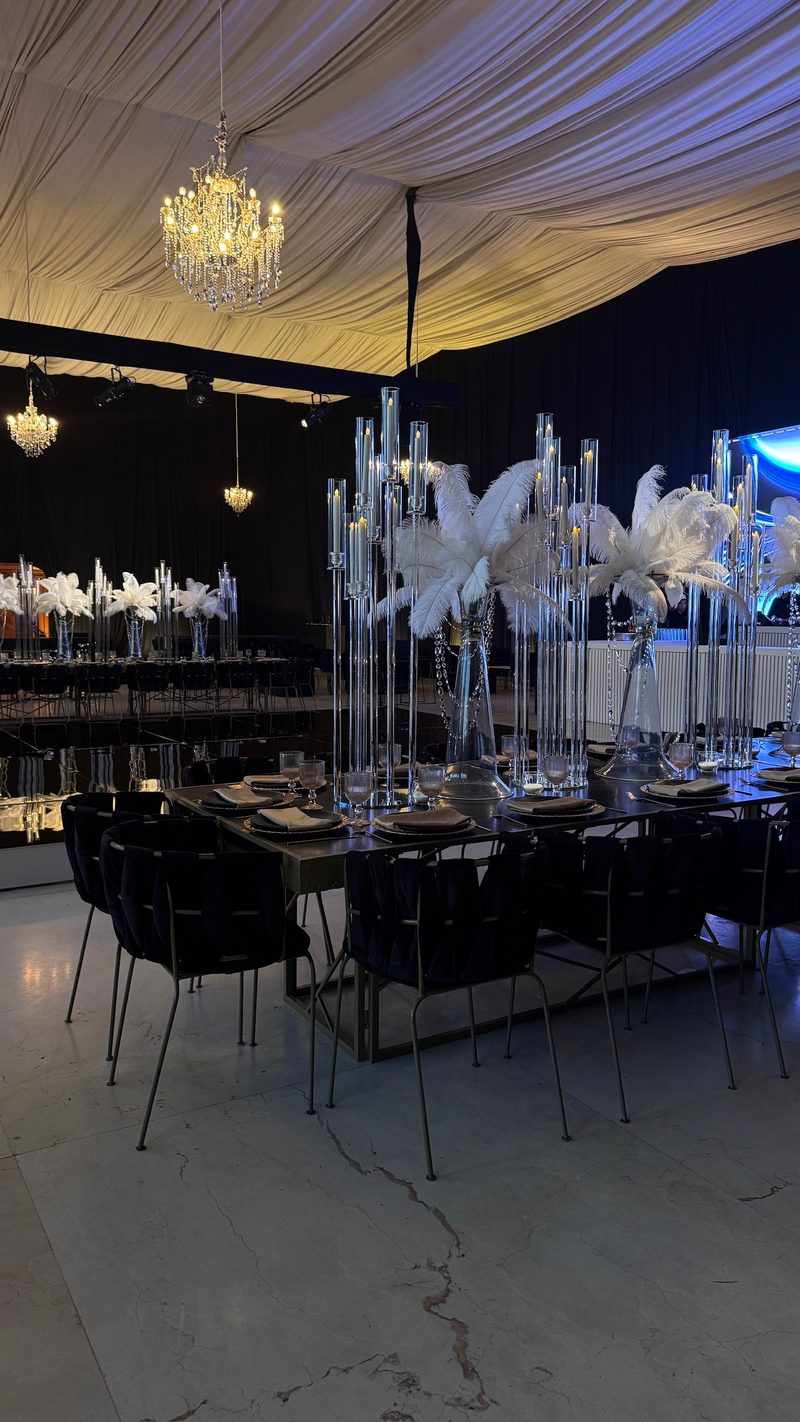 Salón de XV años en negro y blanco con centros de plumas y candelabros de cristal
