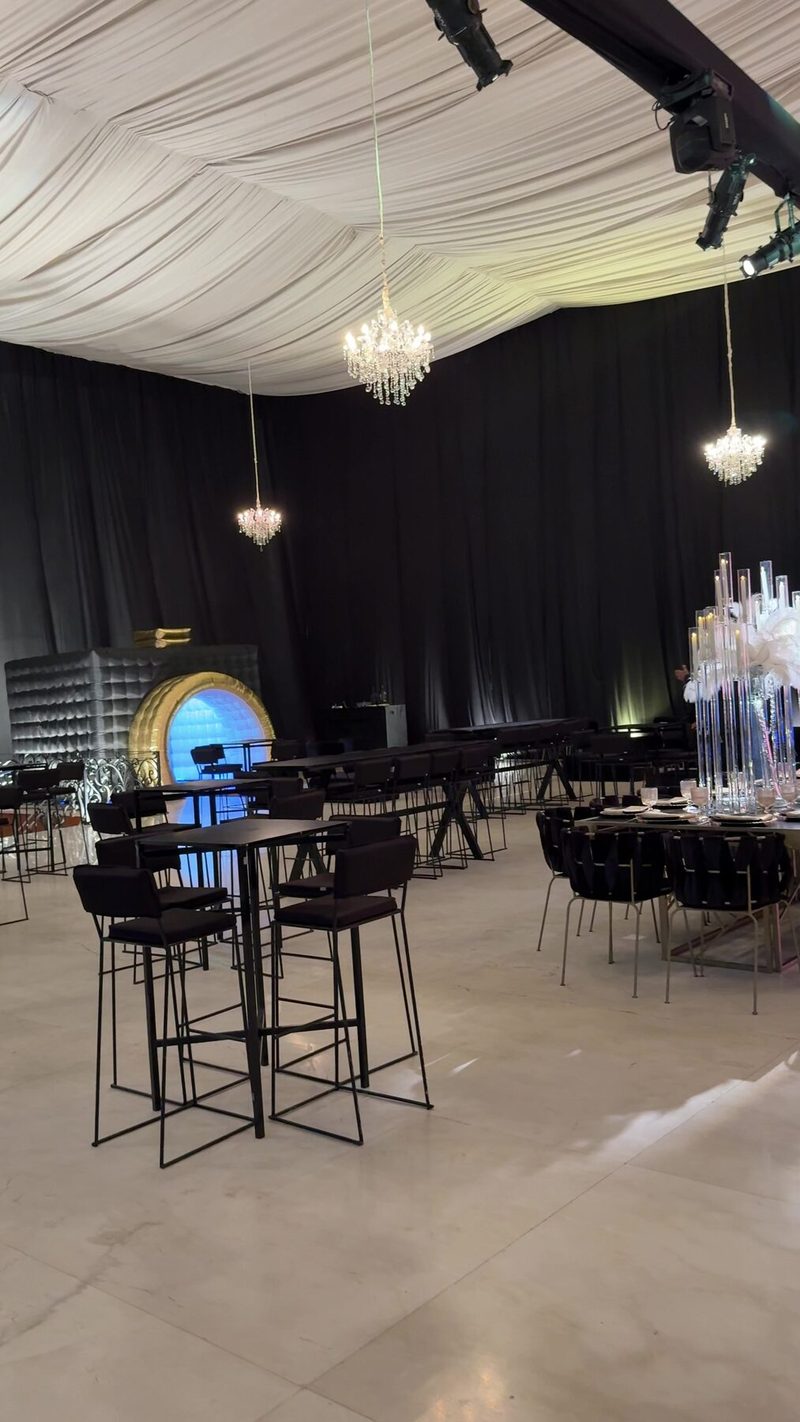 Salón de XV años con mesas de mármol negro, candelabros colgantes y centro de cristal